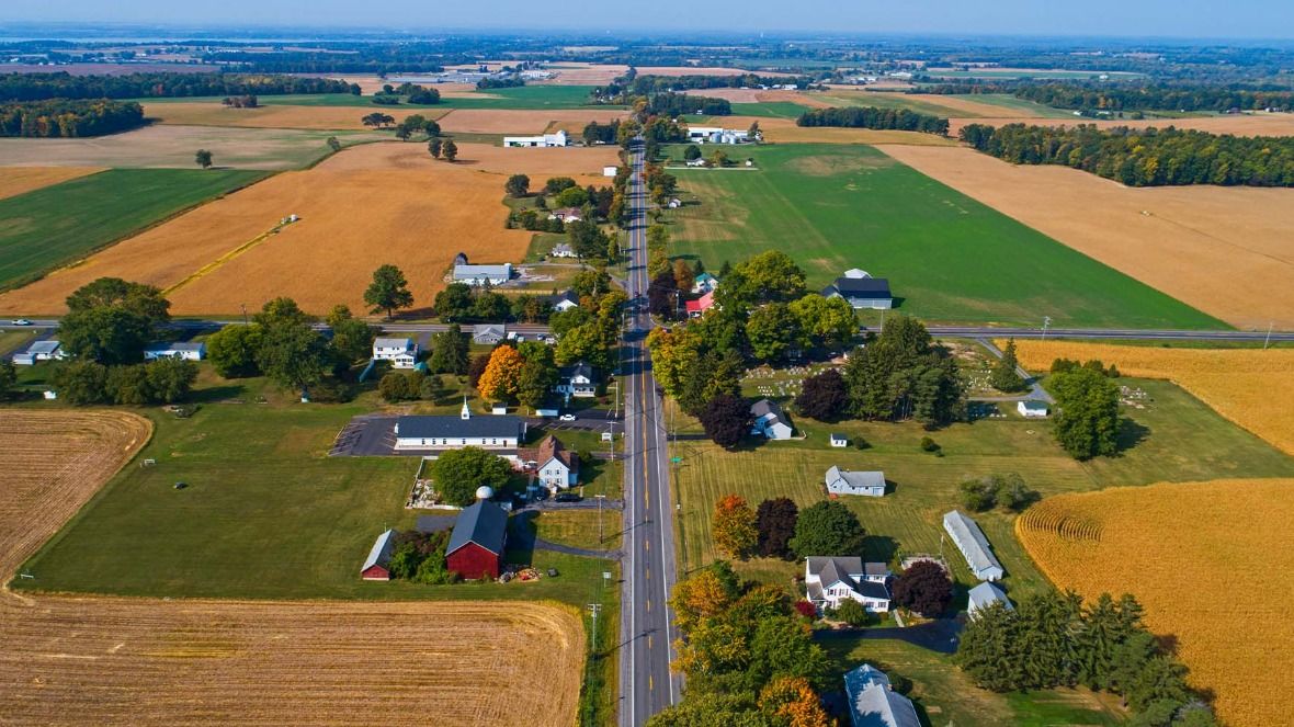 An aerial image of land in Ohio, which has a road with shops and houses alongside it, surrounded by fields
